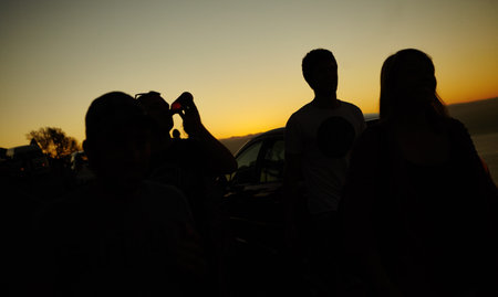 Ending the day with a gorgeous sunset. Silhouette of a group of friends against a yellow sunset.の写真素材