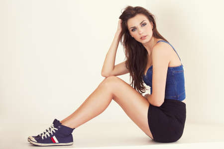 Shes got her own style. Trendy young woman looking at the camera while sitting against a white...