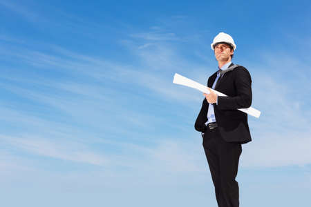 An architect with blueprints standing against clear sky. Business blueprint - An architect with...
