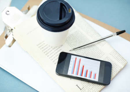 Keeping an eye on the news and the stock market. Smartphone with bar graph on screen sitting ontop...
