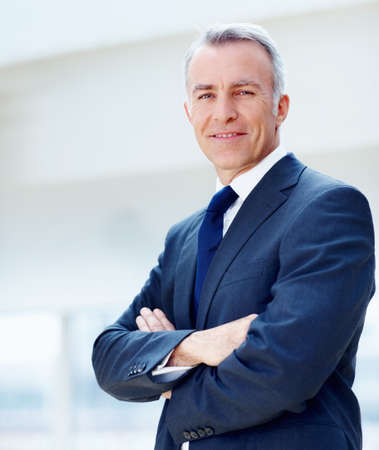 Successful businessman. Executive standing with arms folded.