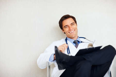 Relaxed doctor with a stethoscope and notepad. Relaxed young doctor with a stethoscope and notepad at hospital.の写真素材