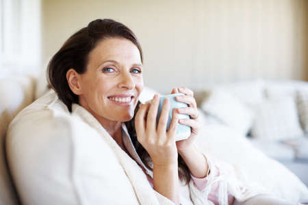 Taking a coffee break at home. Portrait of an attractive woman enjoying a cup of coffee while...