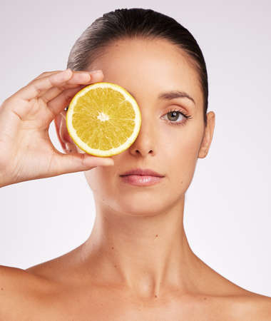 Vitamin C does it for me. Shot of an attractive young woman holding an orange against a studio...