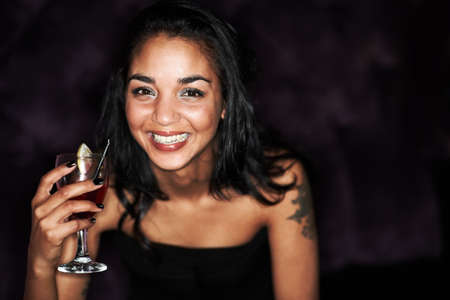 The nights just getting started. A pretty young girl enjoying a cocktail alongside copyspace against a dark background.の写真素材