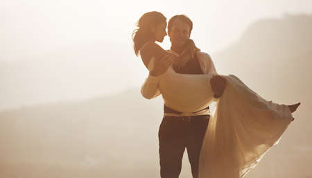 Sunset romance. A groom carrying his bride.の写真素材
