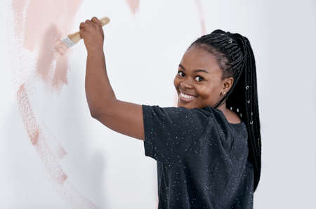 Nothing gives your house personality like a colourful paint job. Shot of a young woman painting a wall pink.の写真素材
