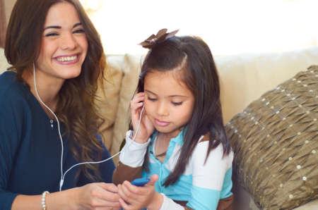 Sharing a love of music. Cute little girl listening to music with her mother.