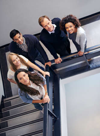 Looking down upon the dream team. Portrait of a group of office coworkers standing in a stairwell.の写真素材