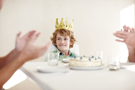The king loves the attention. Shot of two people clapping hands for the birthday boy.の写真素材