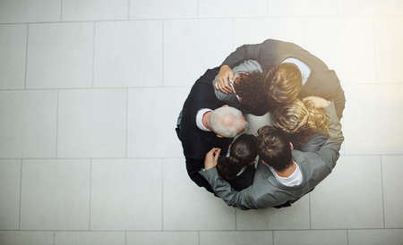The huddle before work. High angle shot of a group of businesspeople standing in a huddle.の写真素材