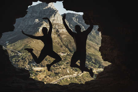 We did it. Rearview shot of a young couple jumping in excitement while hiking in the mountains.の写真素材