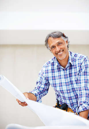 Happy engineer smiling. Portrait of handsome mature architect smiling with blueprint in hand.