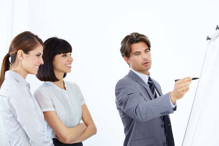 Setting the business plan in order. Three young and ambitious executives strategizing together on a whiteboard.の写真素材