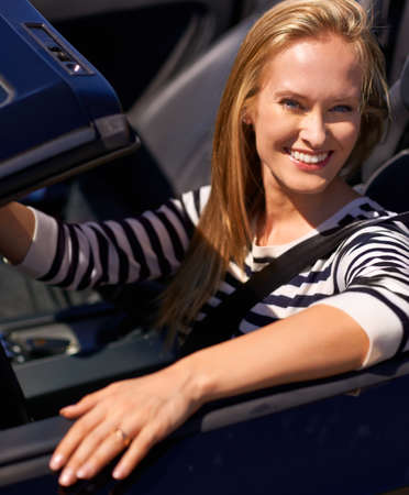 Lets put the pedal to the metal. Shot of a young woman driving in a sports car.の写真素材