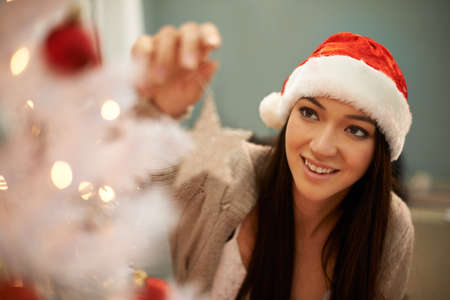 And the star goes on the top. Cropped shot of an attractive young woman decorating a Christmas tree.