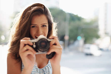 Taking pictures of everything on vacation. Cropped shot of an attractive young woman in an urban setting.の写真素材