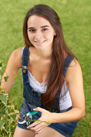 She enjoys gardening. Portrait of a beautiful young woman pruning her hedges.