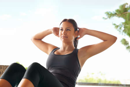 This is easy-peasy for her. Shot of a sporty young woman doing sit-ups outside.