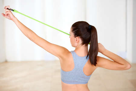 Toning with resistance. A beautiful young woman doing resistance training in the gym.