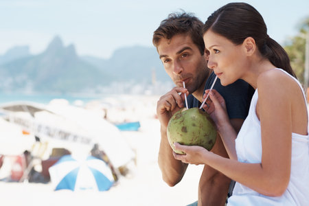 Enjoying something new with the person I love. Young couple enjoying a drink from a coconut while...