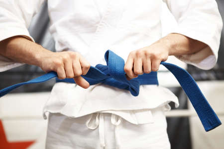 Preparing for battle. Cropped shot of martial artist putting on his gi and tying his belt.の写真素材