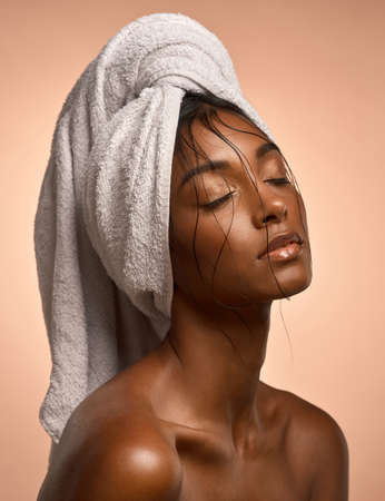 Rev it up to levitate her. Shot of a beautiful young woman with her hair wrapped in a towel against a brown background.の写真素材