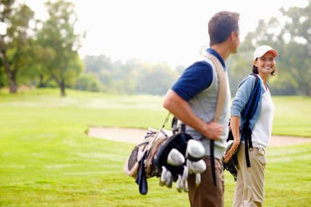 Female golfer smiling and looking at man. Focus on female golfer smiling and looking at man.の写真素材