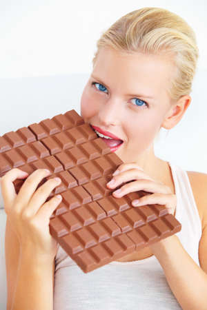 Ill only eat a little of it.... Young woman biting into a huge bar of chocolate.
