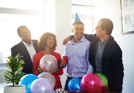 Celebrating office birthdays. Shot of a coworkers having a office birthday party.の写真素材