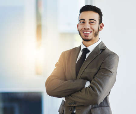 Here to show the business world what Im made of. Portrait of a confident young businessman standing in an office.の写真素材