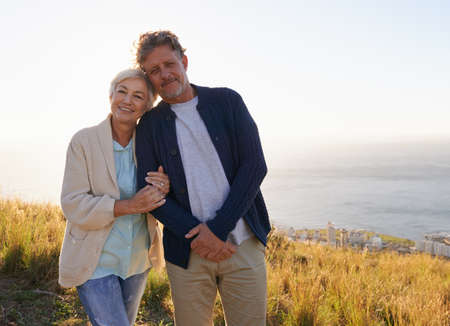 Committed to loving one another. View of a senior couple standing on a hillside together.の写真素材