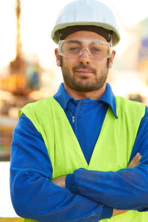 Professional - Hell get the job done. A stern construction working wearing protective glasses and crossing his arms.の写真素材