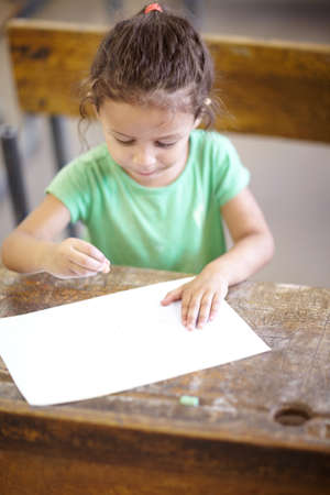 Showing her creativity. Sweet little girl sitting at a school desk and drawing.の写真素材