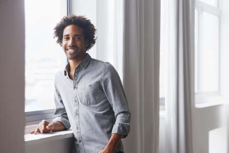 Living every day as an optimist. A portrait of a happy young man standing and leaning against a...