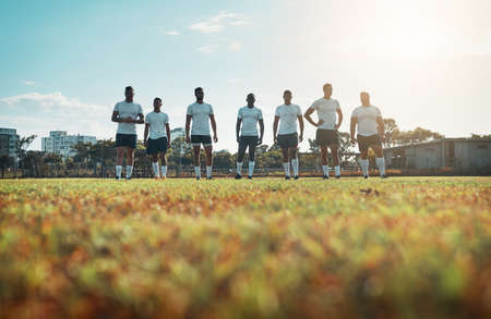 Teamwork leads to huge success on the field. Rearview shot of a group of young rugby players standing on a field.の写真素材