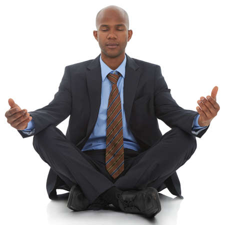 Clearing his mind. An African-American businessman sitting meditating against a white background.の写真素材