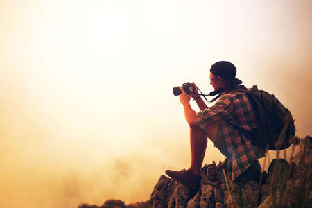 Photography is a love affair with nature. Shot of a young photographer taking a picture of a foggy...