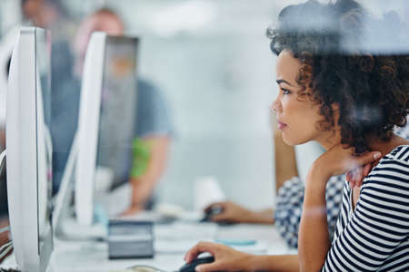 Trouble shooting tech is my specialty. Shot of a young office worker sitting at her workstation in...