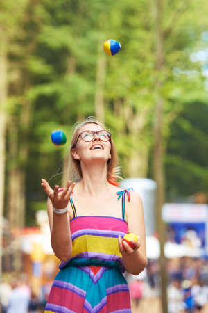 Her juggling skills are on the ball. Shot of an attractive young woman juggling at an outdoor festival.の写真素材