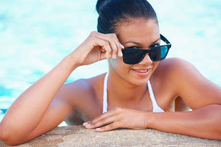 Ready for a summer fling. Cropped view of a young woman in a swimming pool smiling while wearing...
