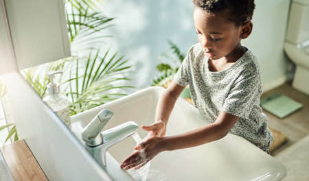 Kids should wash their hands often with soap and water. High angle shot of a boy washing his hands...