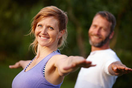 Staying in great shape. Shot of an attractive woman doing yoga with her partner in the outdoors.の写真素材