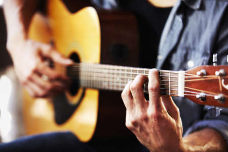 His skill has been gained through hours of practice. Cropped view of masculine hands strumming a...