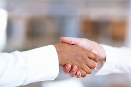 Firm handshake. Closeup of multiracial handshake between two business men.の写真素材