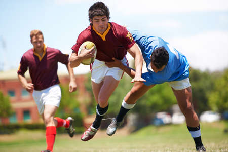 Almost there.... Full length shot of a young rugby player trying to avoid a tackle.の写真素材