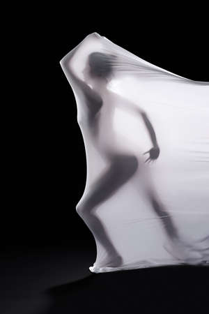 The hardest prison to escape is your mind. Studio shot of a woman wrapped in fabric against a black background.の写真素材