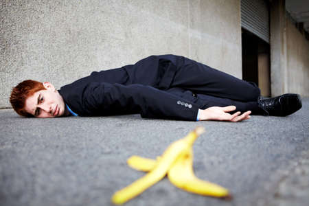 Sometimes banana skins are unavoidable. A young man lying on the ground after slipping on a banana peel.の写真素材