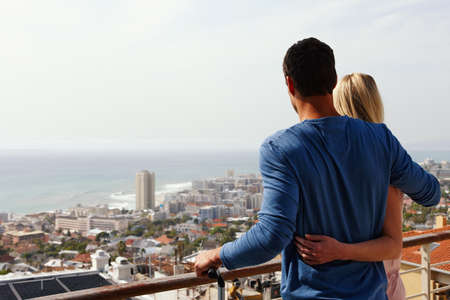 We love our new place. A happy couple standing on a balcony looking over the view.の写真素材