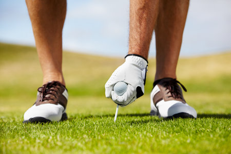 The beginning of the hole. A golfer putting his tee into the ground on the golf course.の写真素材
